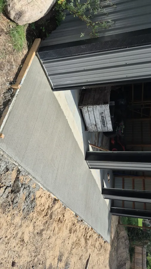Narrow concrete walk poured along the side of a house, forms still in place